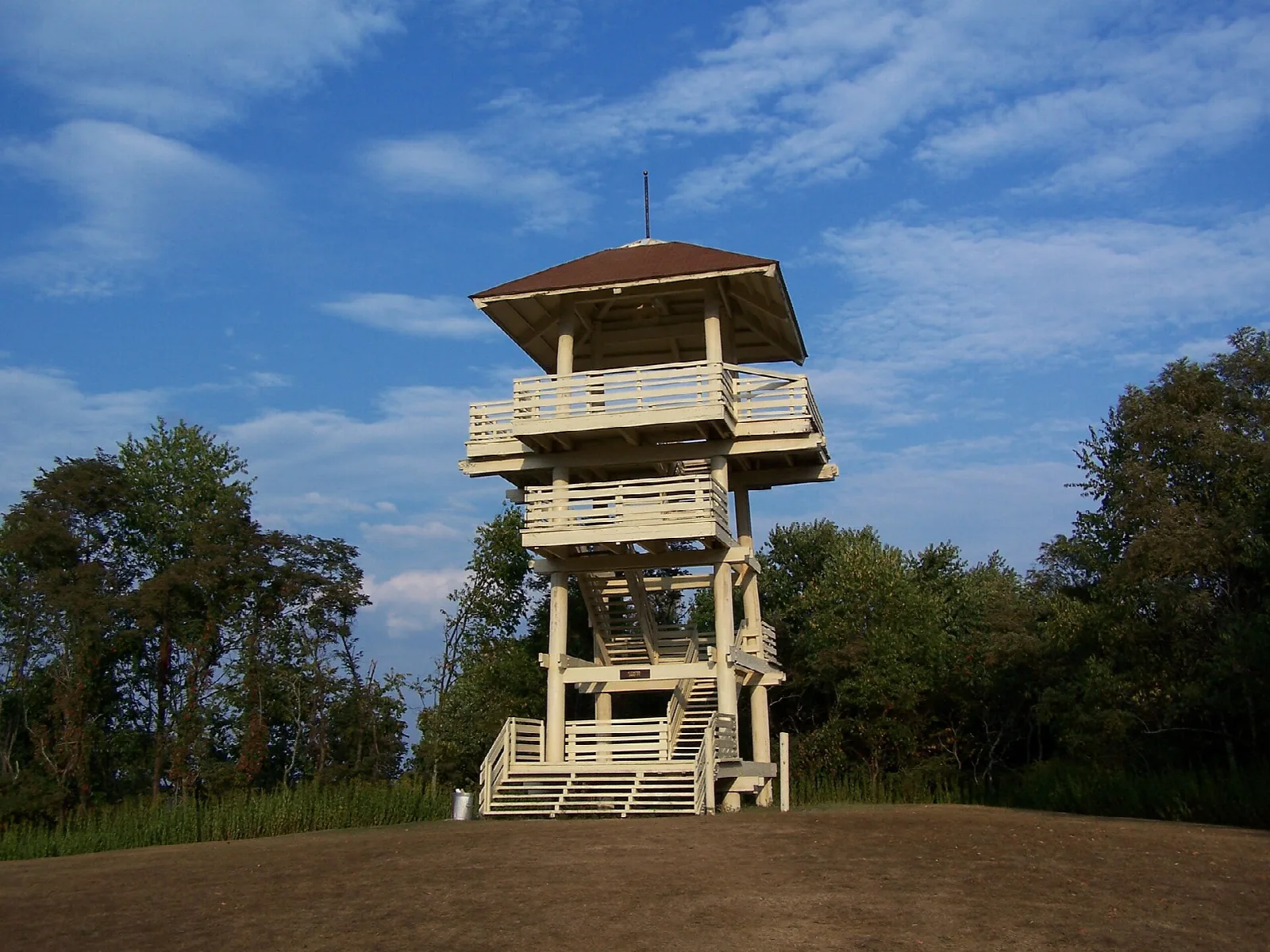 Wooden lookout tower on a grassy hilltop under blue sky