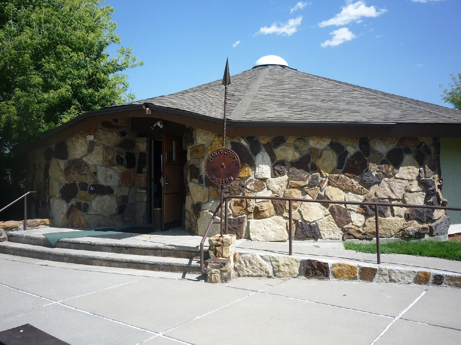 Round-roofed building faced with mixed stone beside a paved walkway
