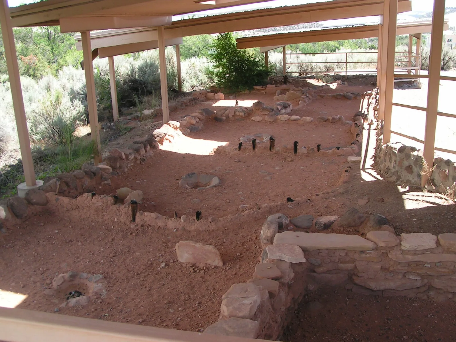 Excavated stone room foundations under a covered shelter