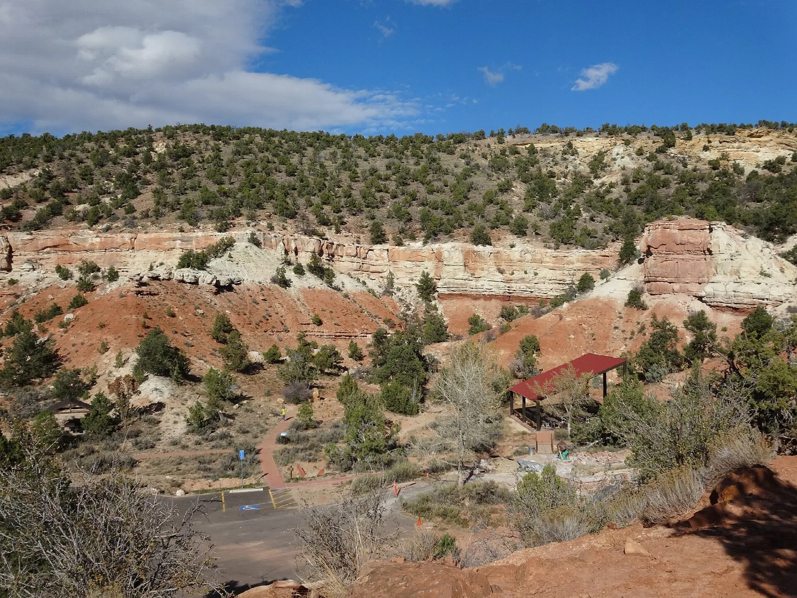 Red and white rock hills with juniper trees above a small developed area