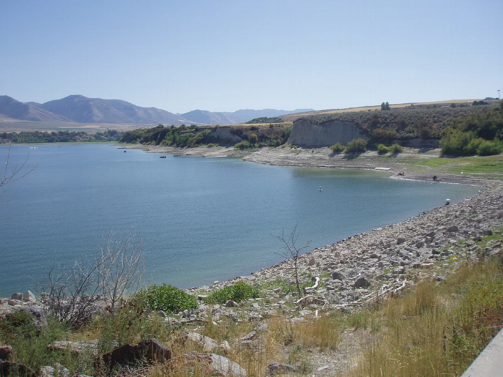 Reservoir with a rocky shoreline and low mountains in the distance