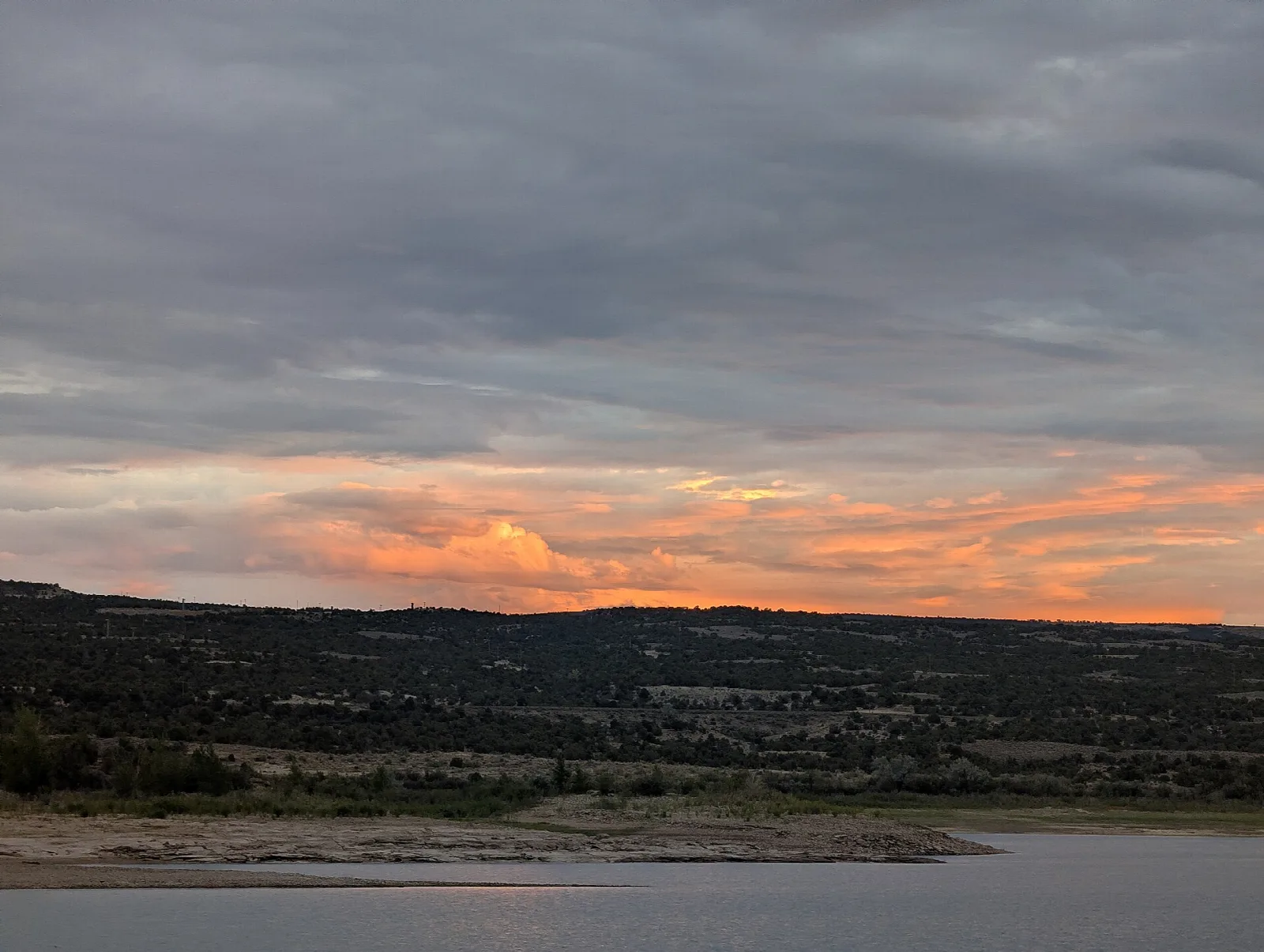 Orange glow along the horizon over a reservoir shoreline