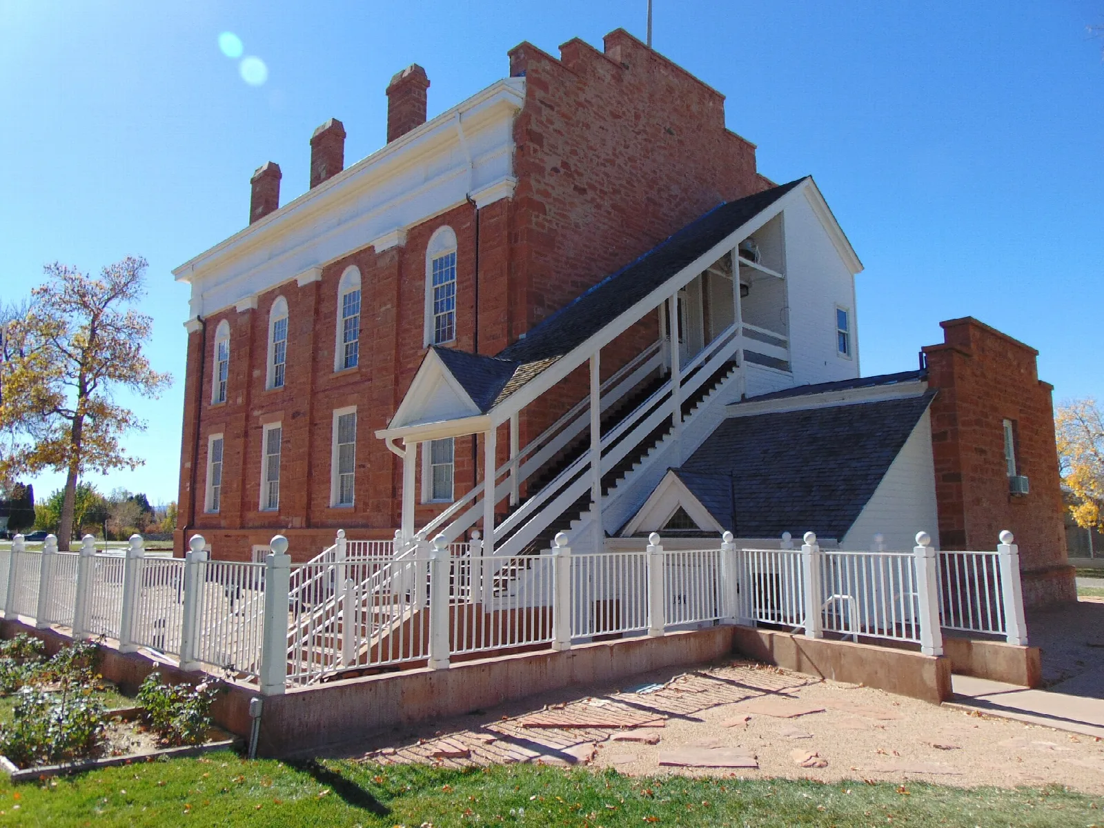 Red brick statehouse seen from the side with a white porch and railing
