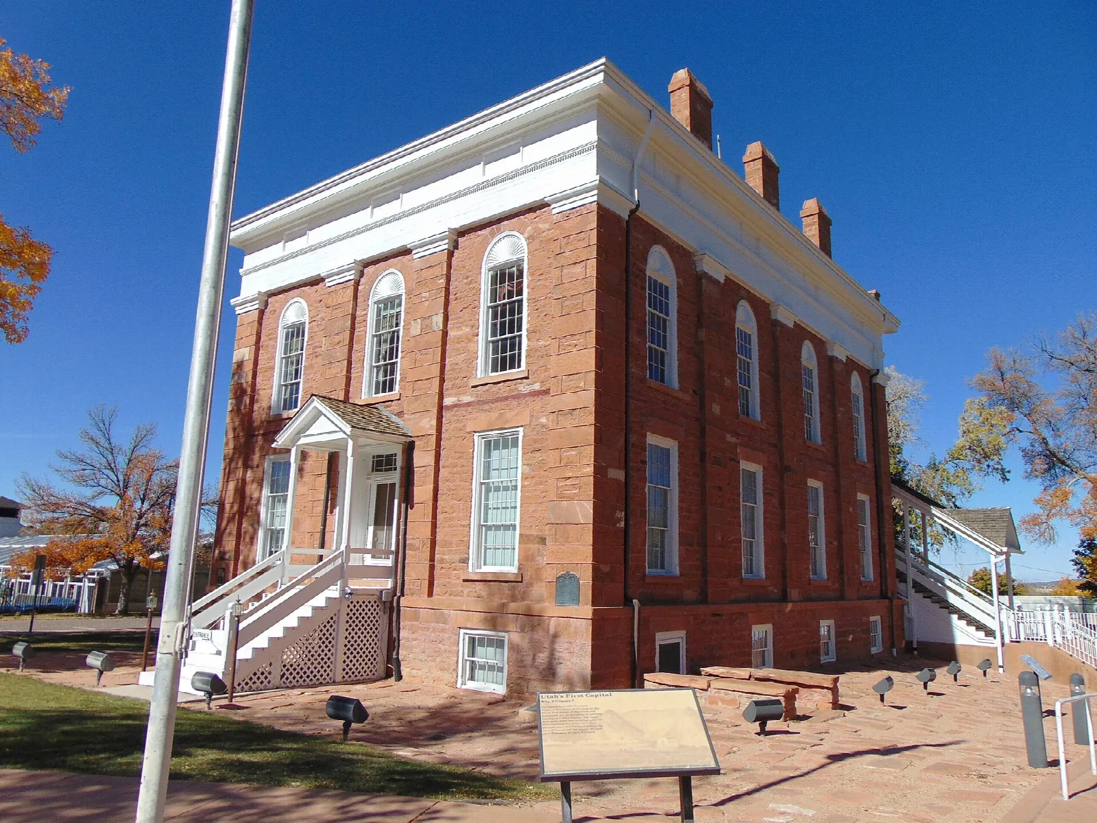 Red brick statehouse corner with white trim under a bright blue sky