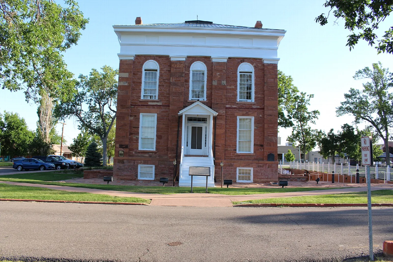 South front of a red brick statehouse with white cornice and a lawn