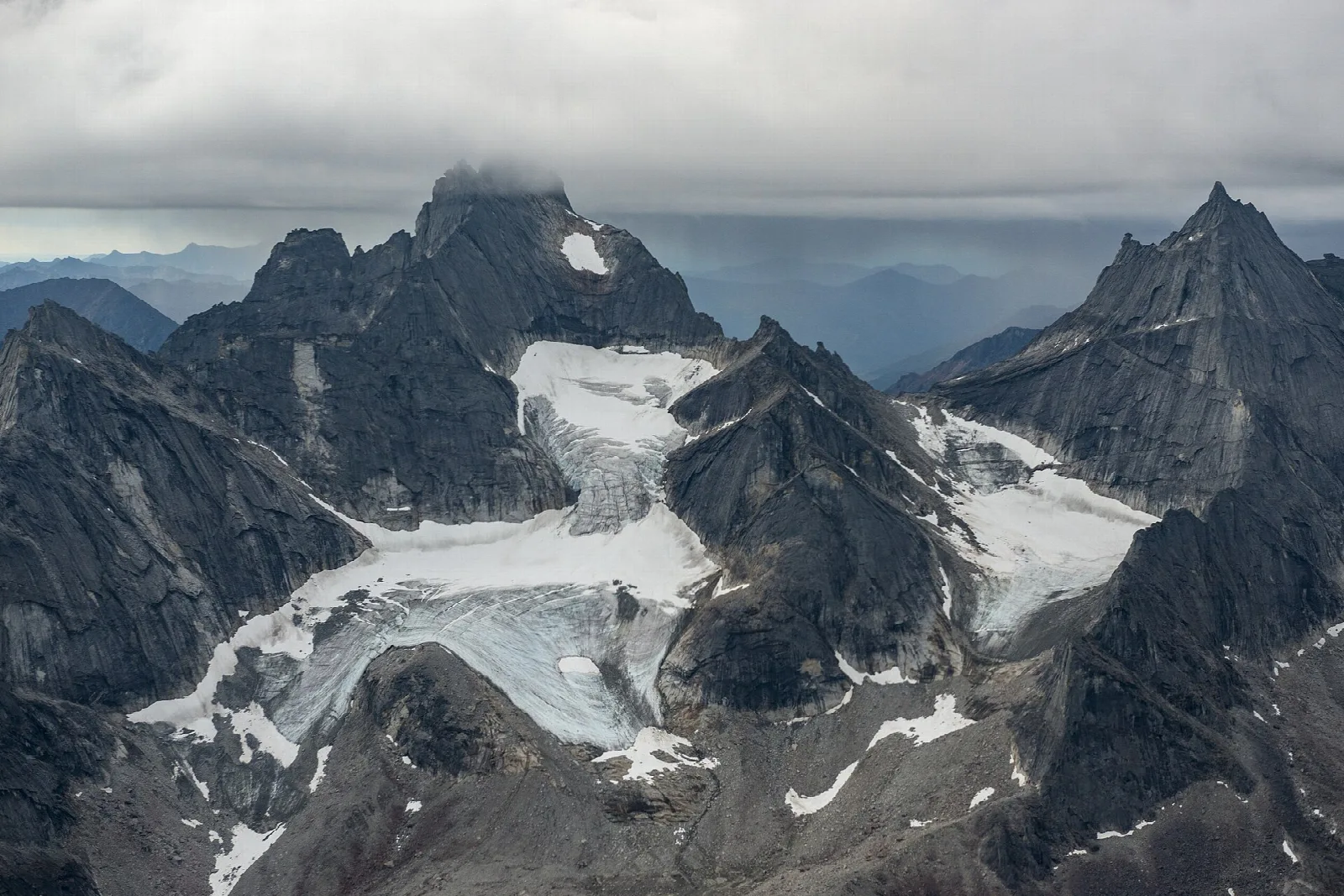Jagged dark granite peaks cradling small white glaciers