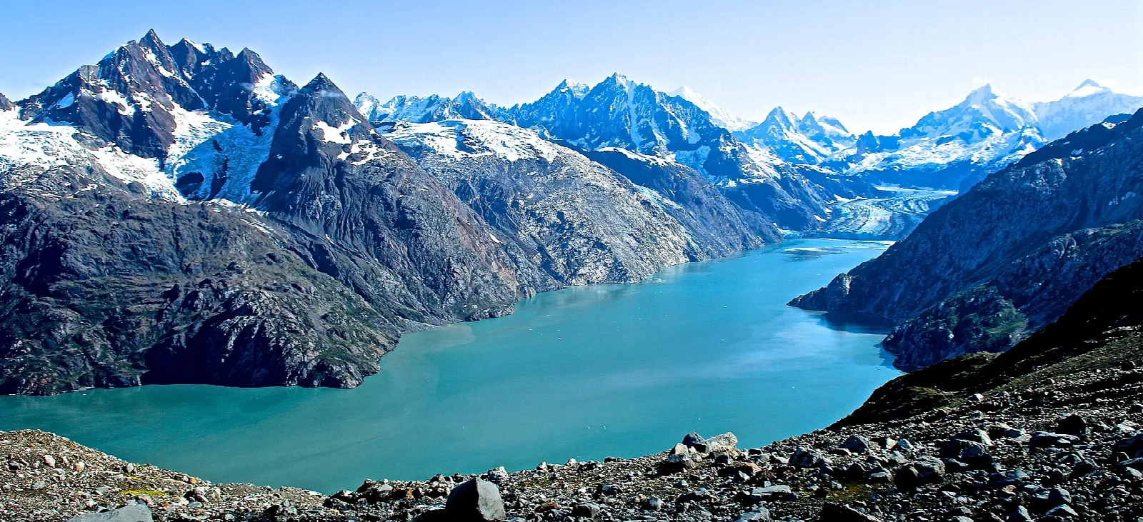 A long turquoise inlet between steep, snow-capped mountains leading to a glacier