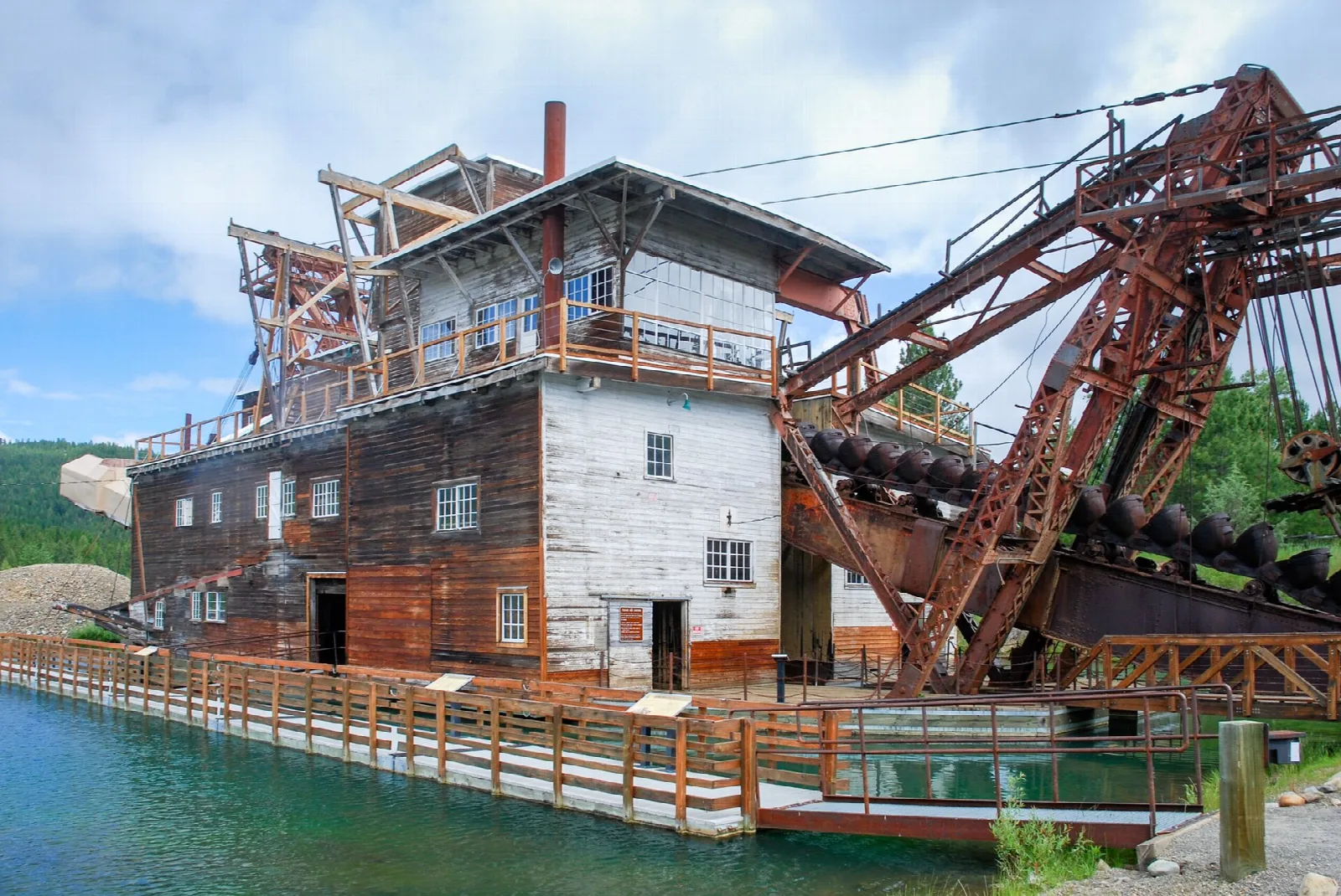 Weathered wooden dredge building with a boardwalk beside the pond