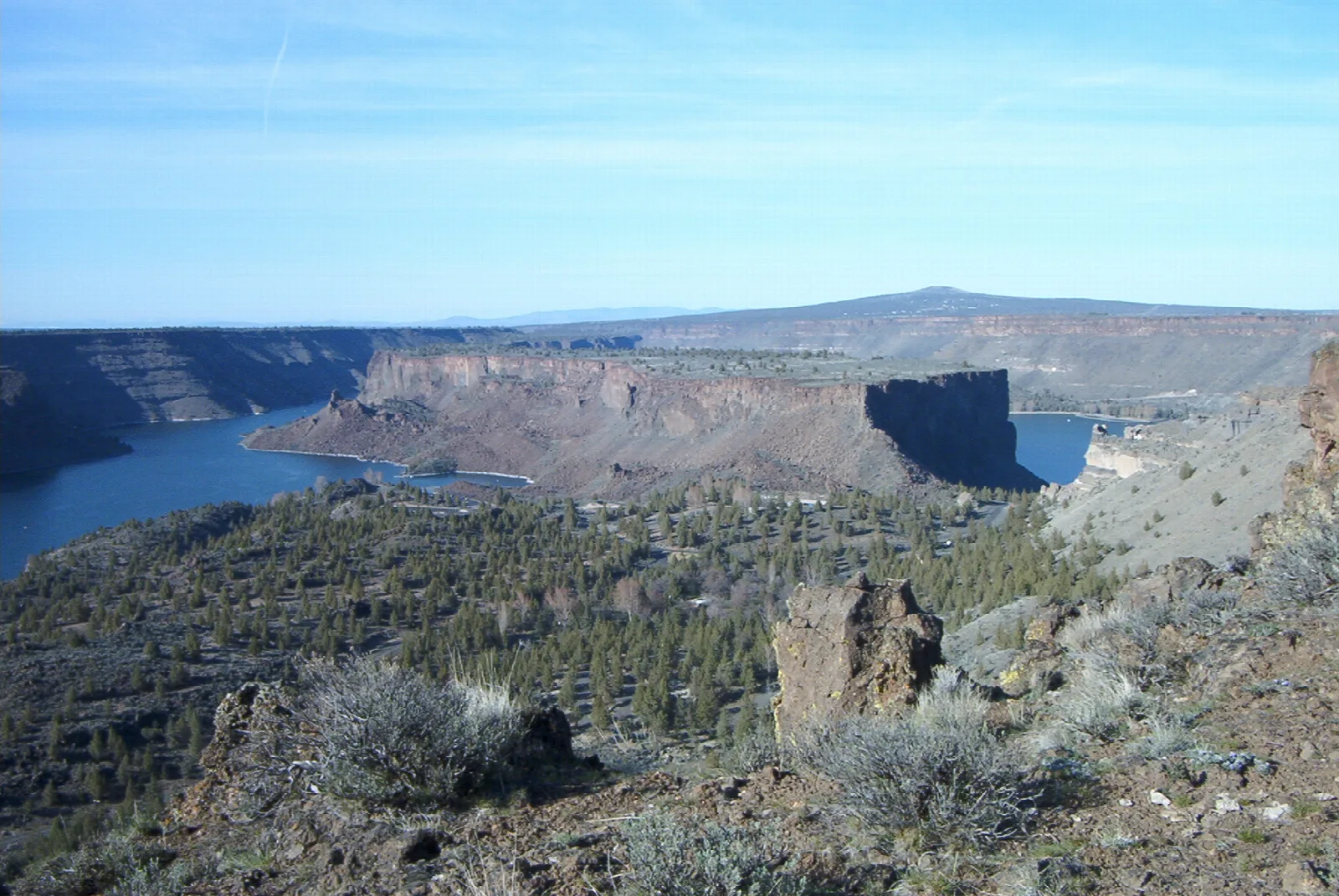 Wide canyon with a blue lake below flat-topped basalt cliffs