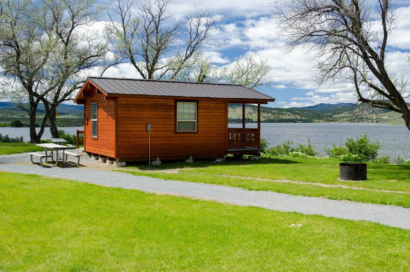 Orange cabin with a porch and picnic table near the water