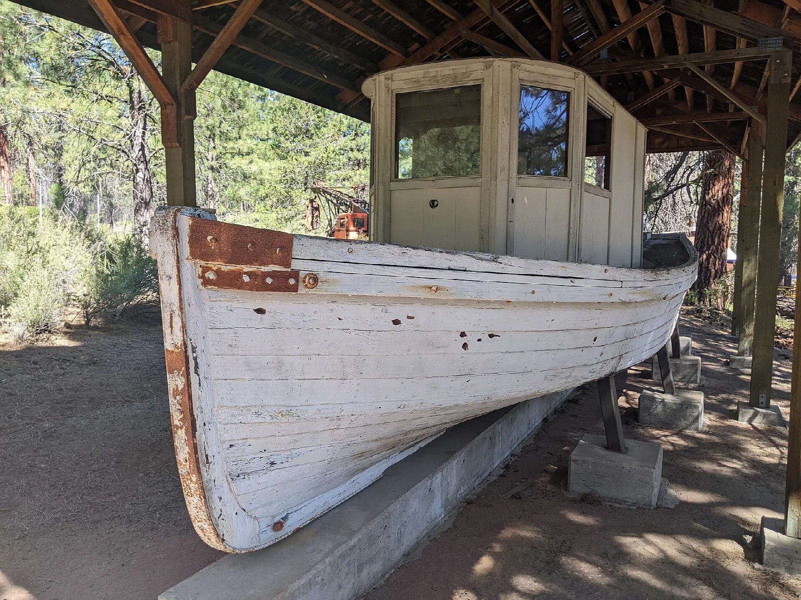 White wooden boat with a cabin sitting under a roofed shelter