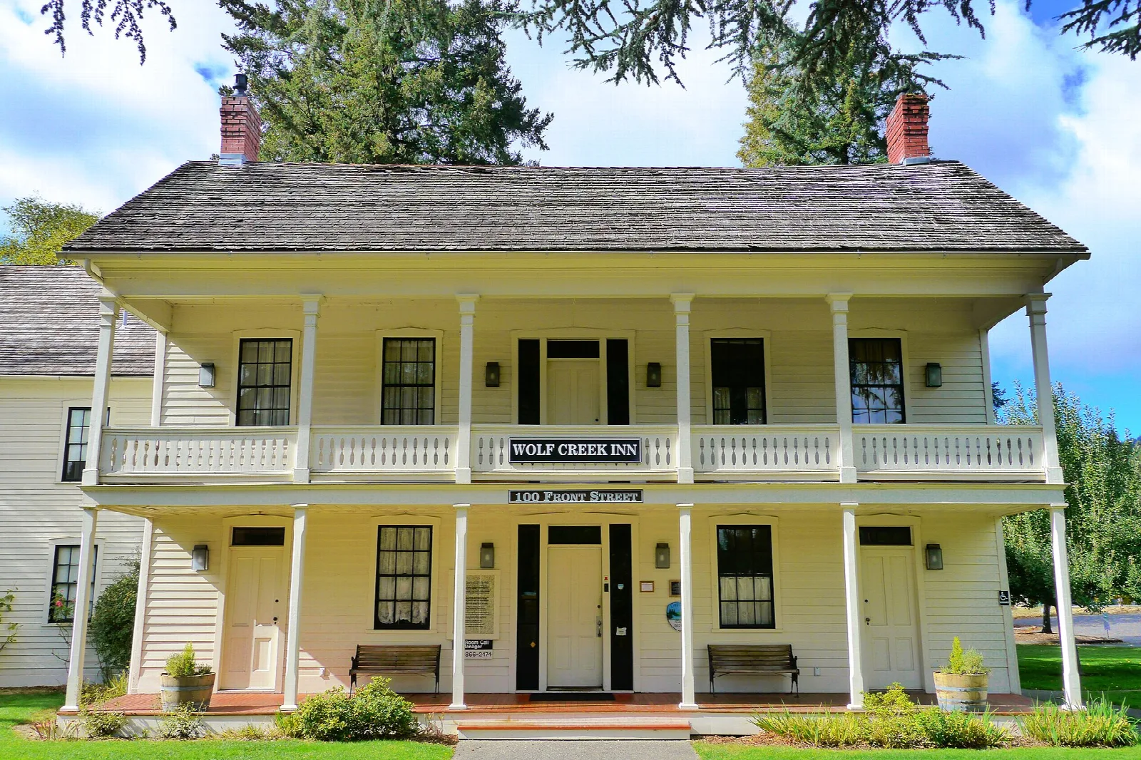 Two-story white inn with a long upper porch and green lawn