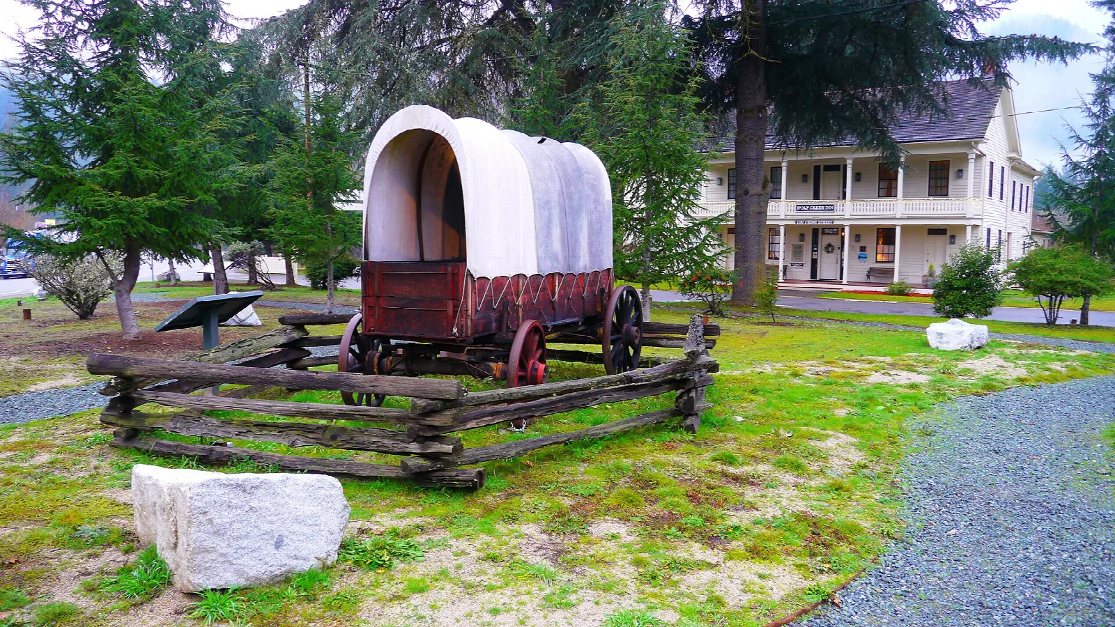Covered wagon replica on a lawn with the inn behind