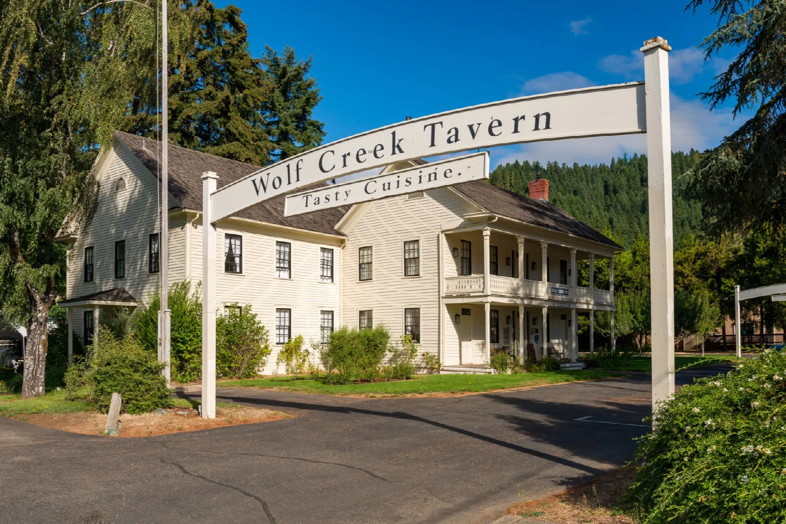 Inn behind an arched Wolf Creek Tavern entrance sign
