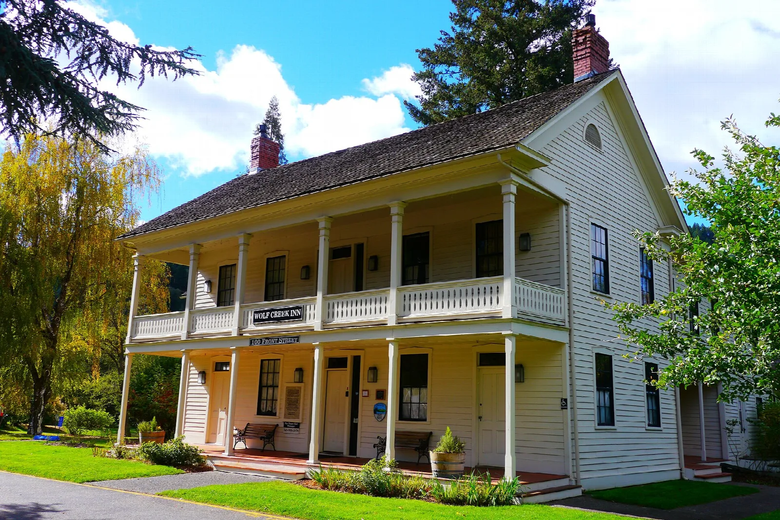Historic inn with two-story porch beside a tree with fall color