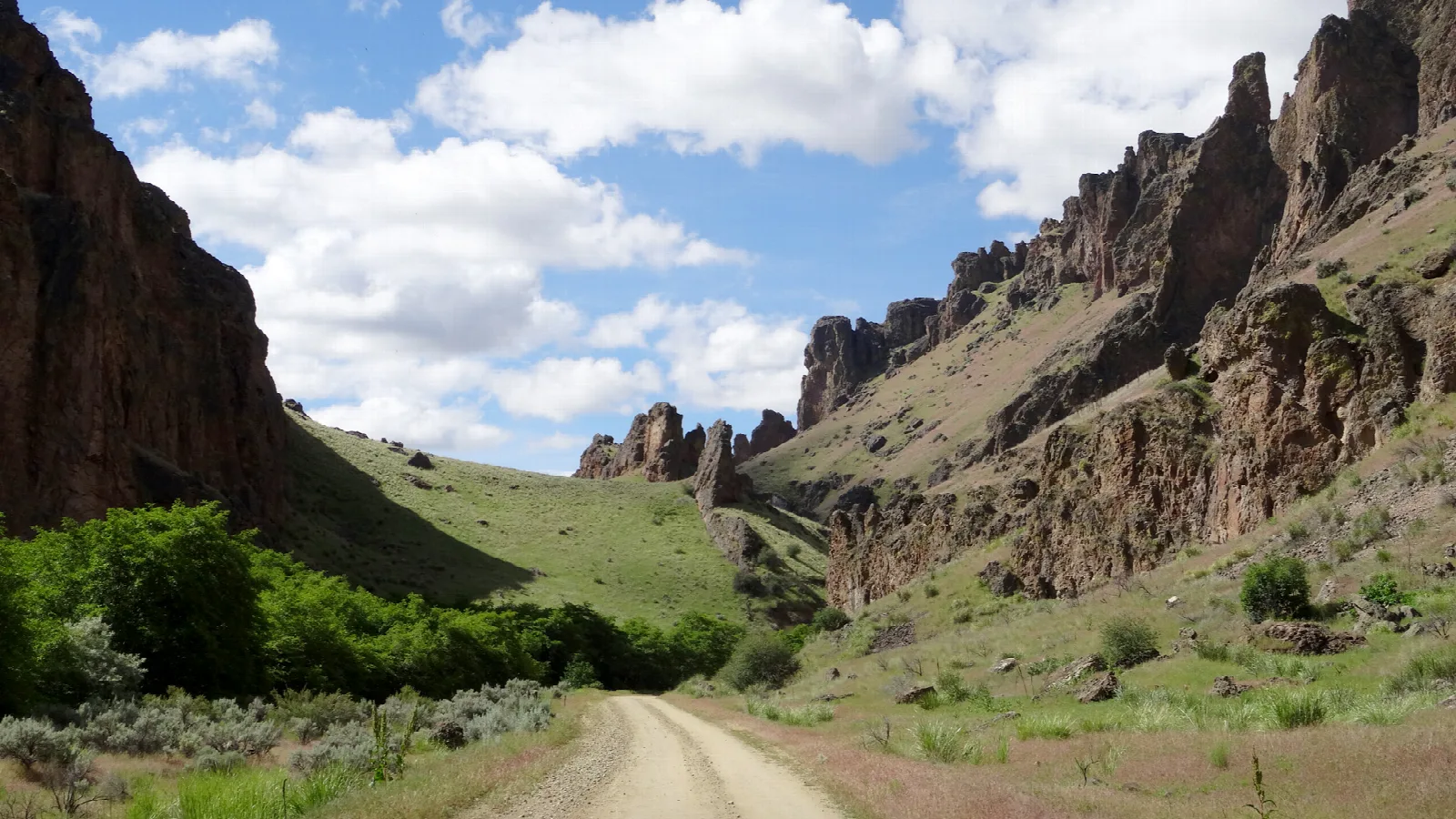 Dirt road winding through a narrow canyon with tall rock walls