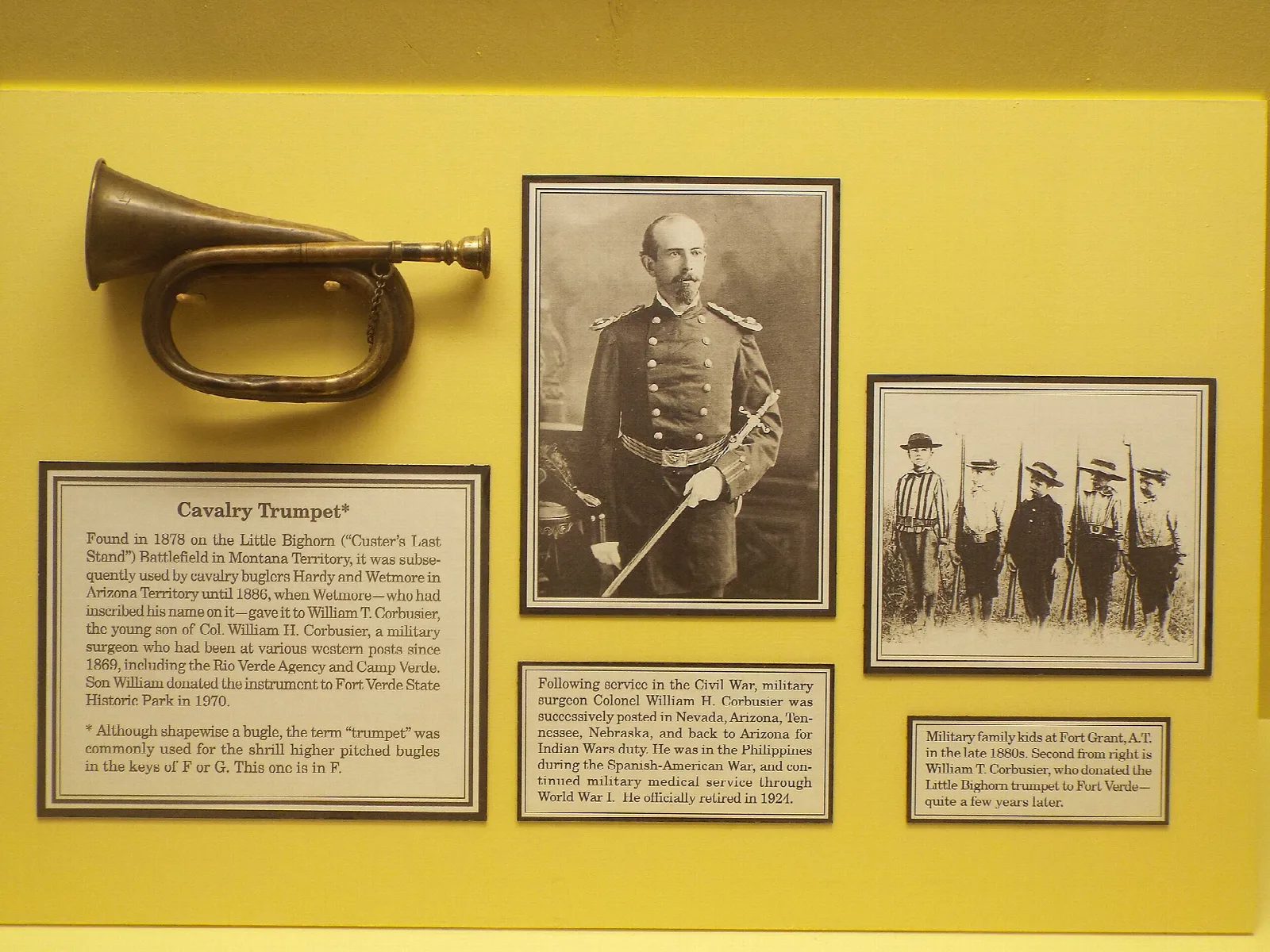 Cavalry trumpet and historic photos on a yellow museum wall
