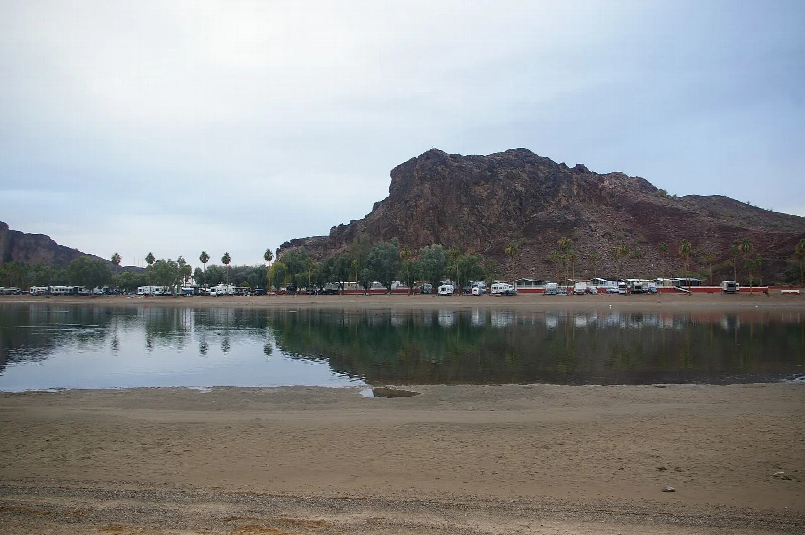 Colorado River with a rocky mountain behind a row of vehicles on the far shore