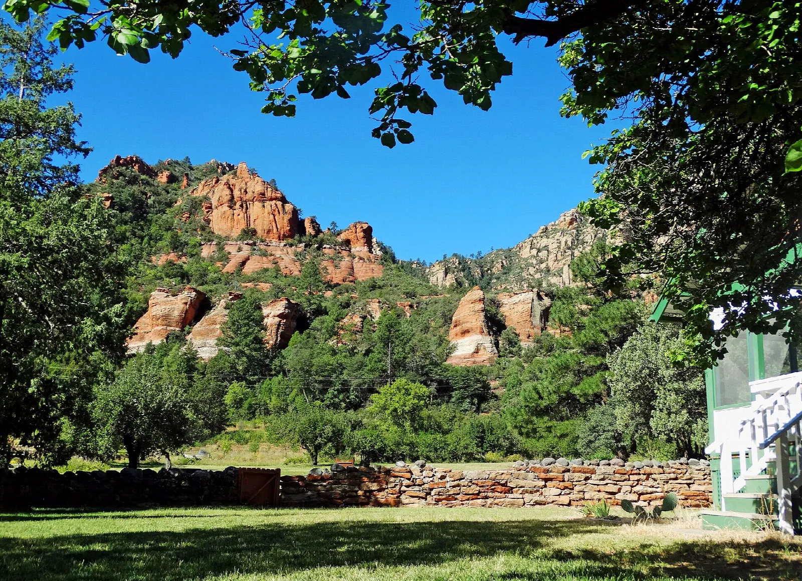 Red rock hills seen through trees from a lawn