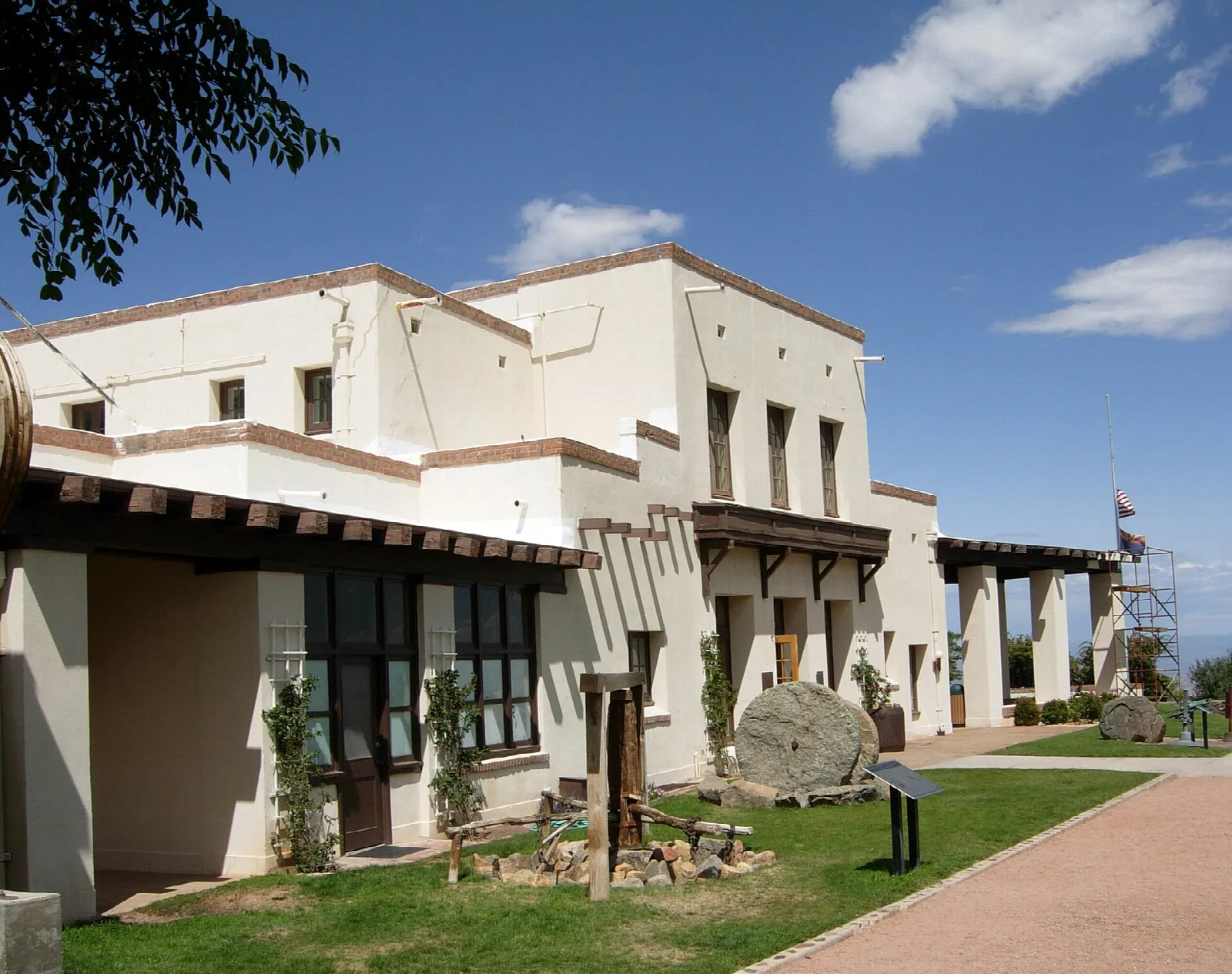Cream-colored adobe mansion with a tiled porch and green lawn