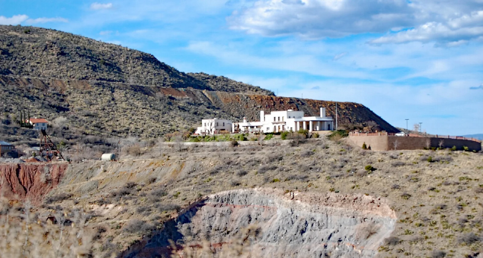 White mansion on a hill above a mine pit and desert slopes