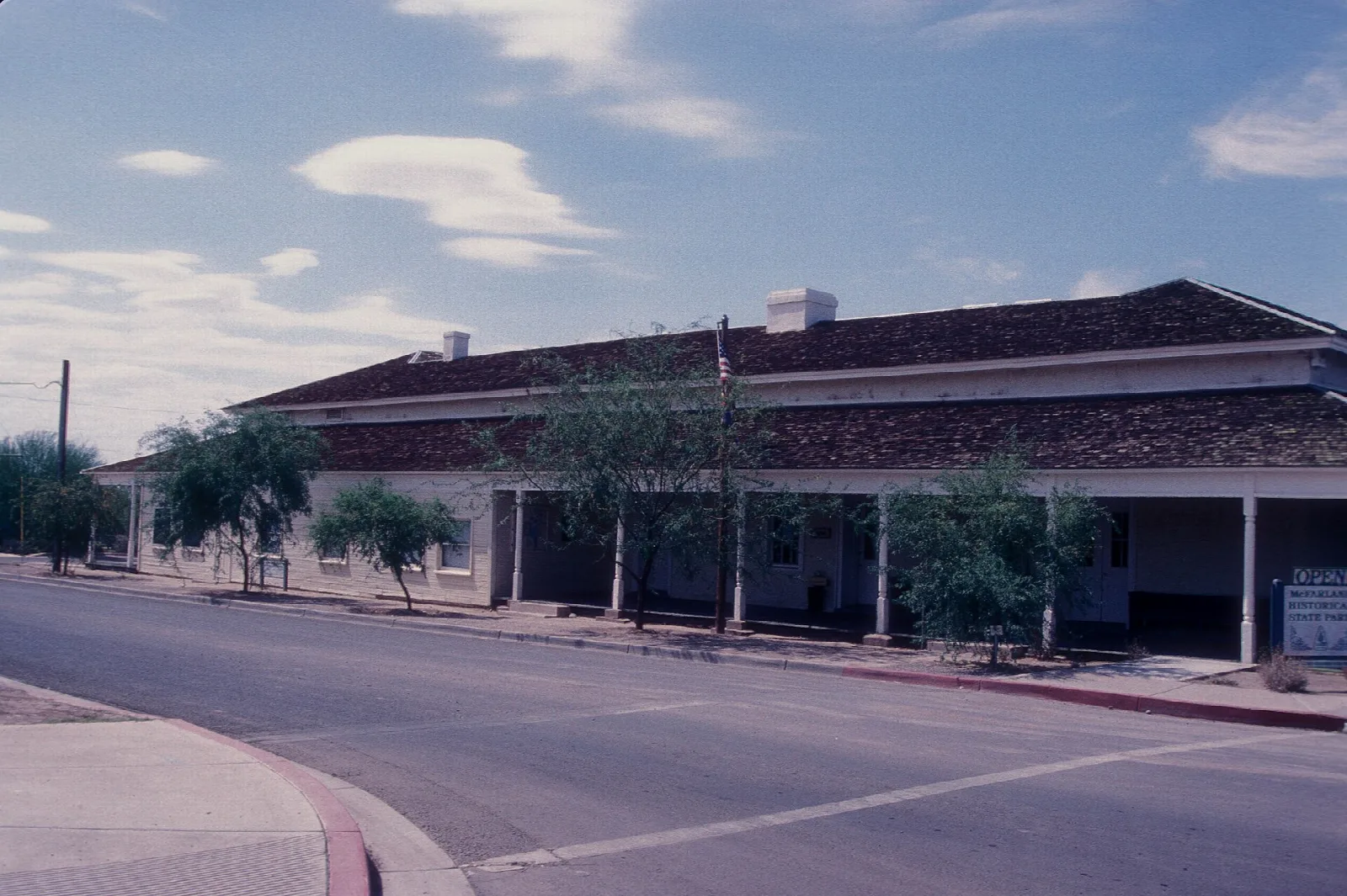 Long low adobe courthouse with a covered porch beside a street