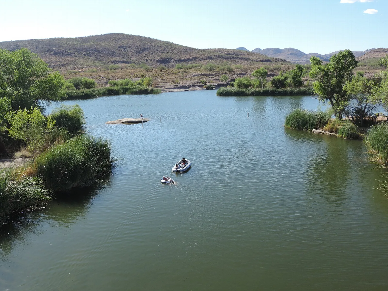 Calm lake channel with a small boat among trees