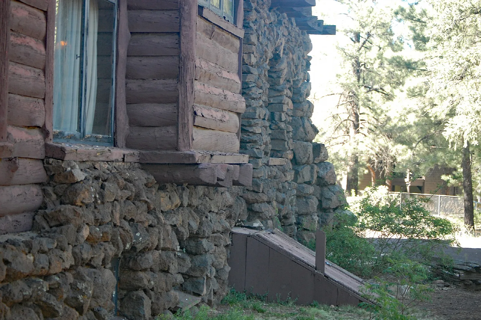 Log-slab siding, a window and a rough volcanic stone wall on the side of the house