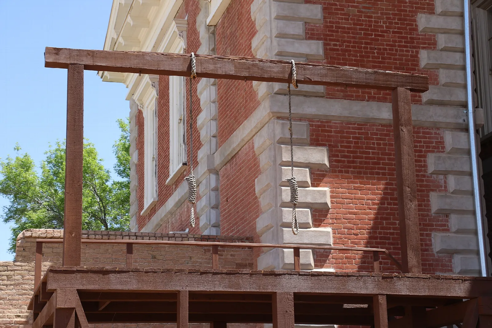 Wooden gallows beside the red-brick courthouse wall