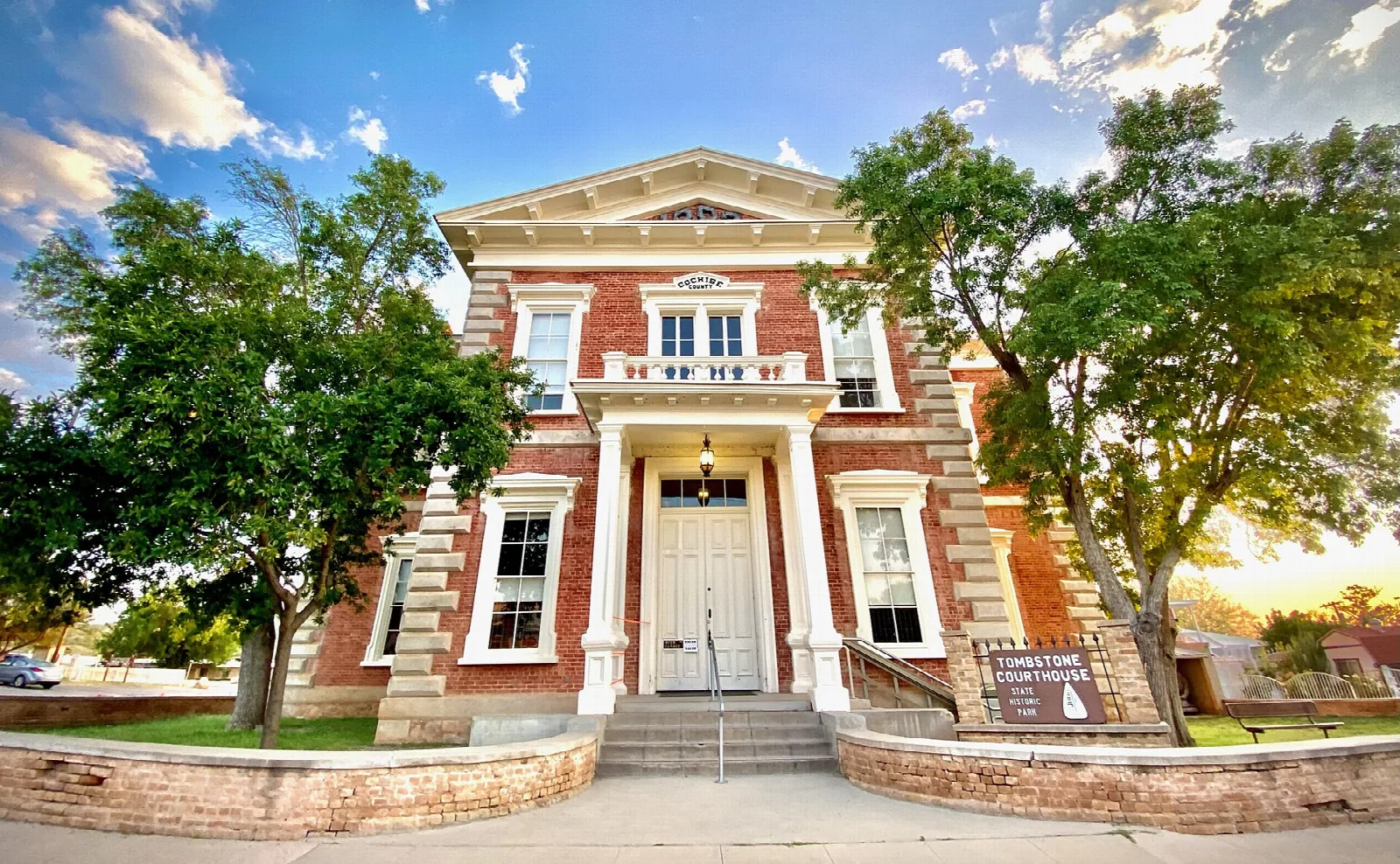 Front steps and entrance of the brick courthouse under blue sky and trees
