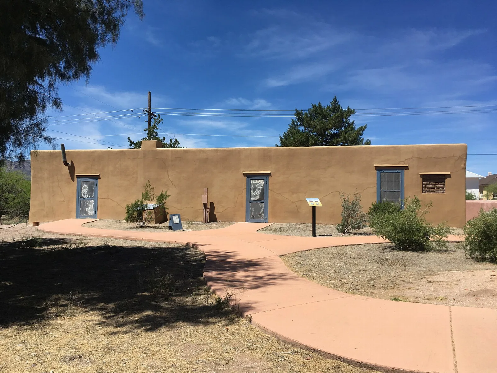 Long low adobe house with doors and a curving path in front