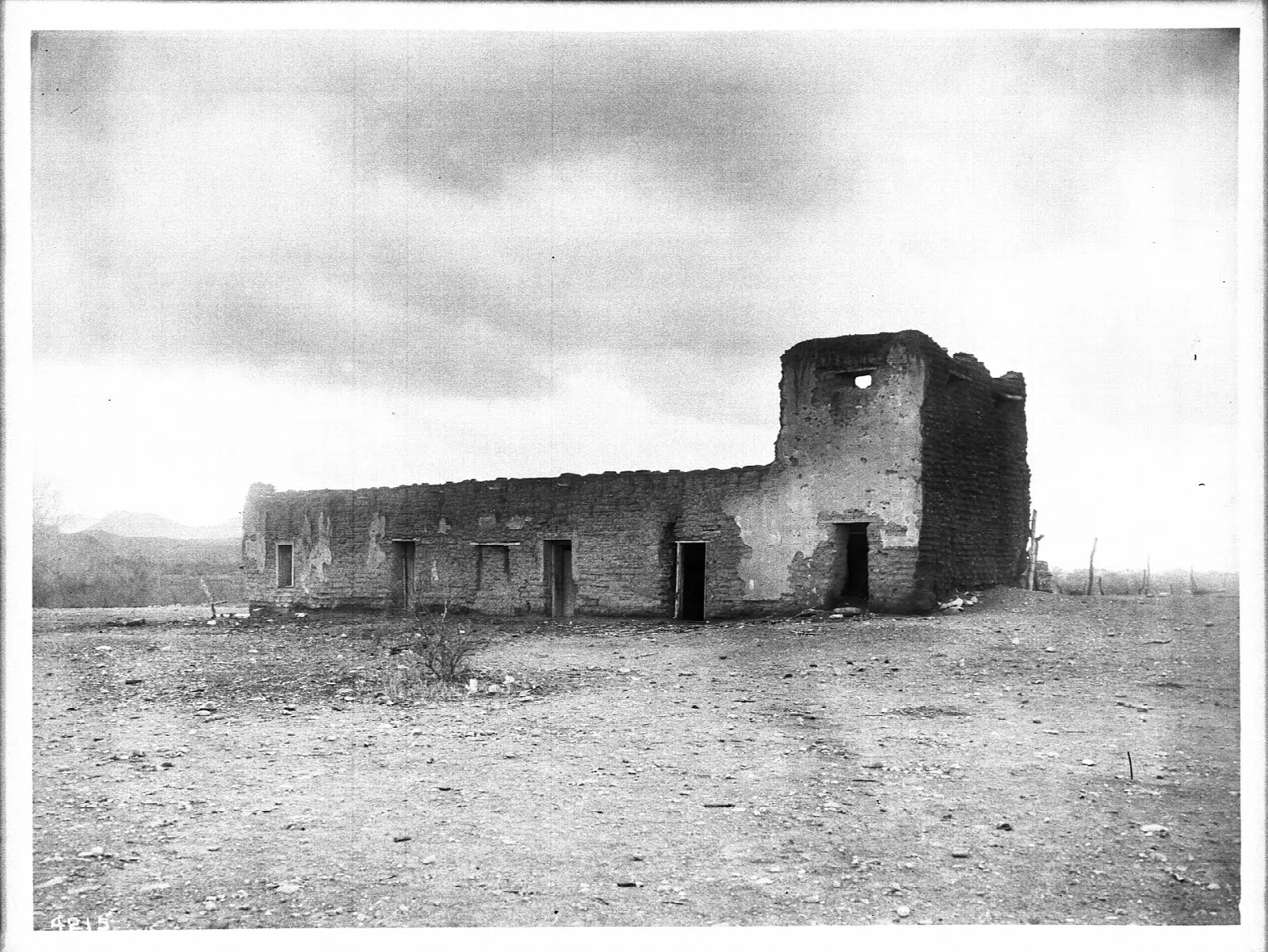 Old black-and-white photo of adobe fortress ruins on an open plain