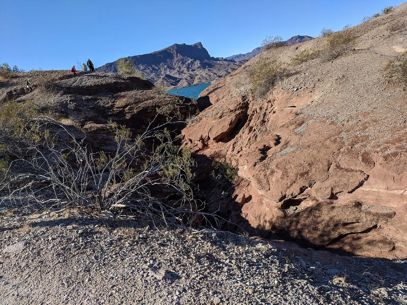 Red rock cut along a desert trail with the lake in the distance