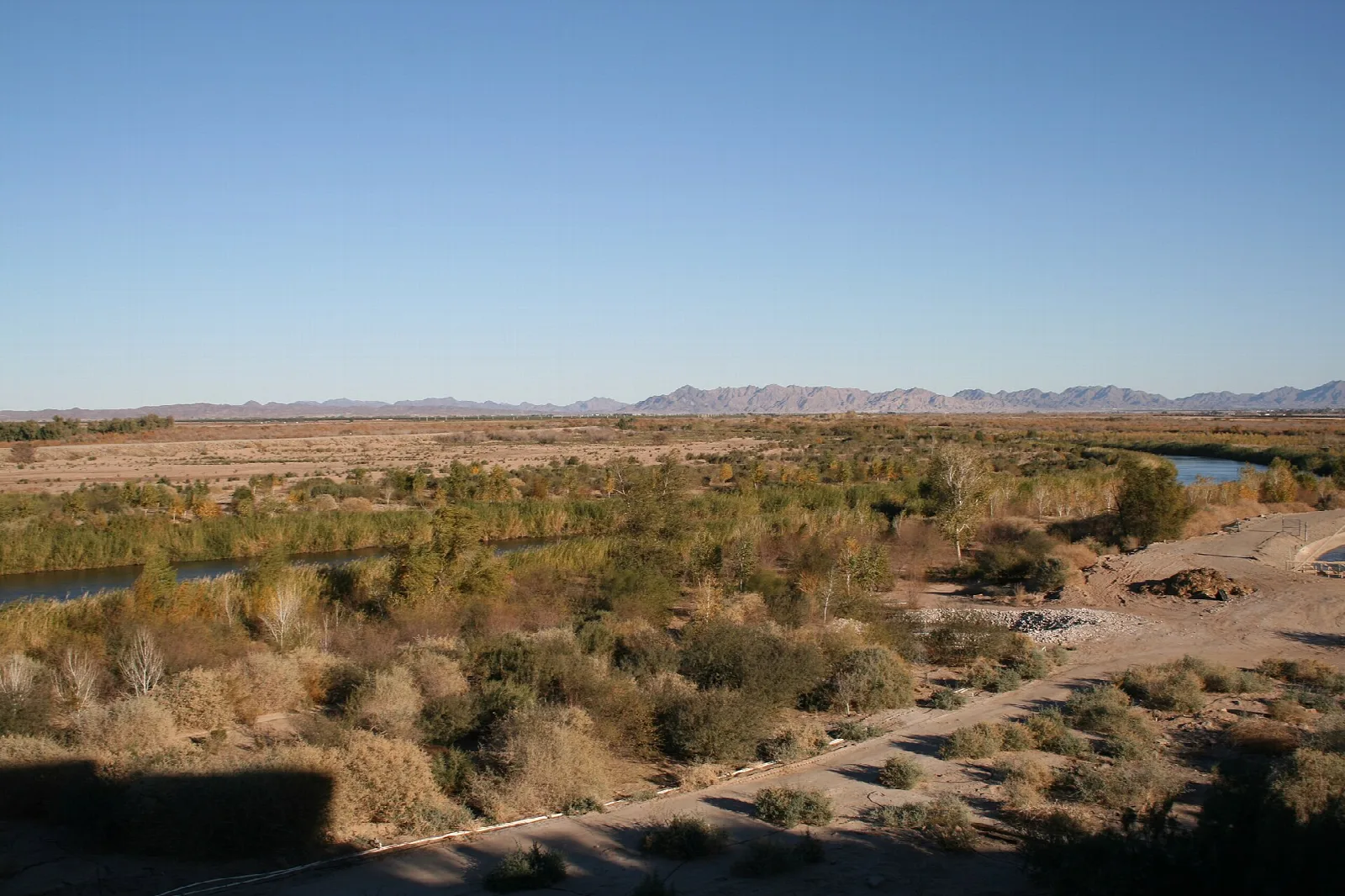 Green river valley with desert hills in the distance seen from the prison