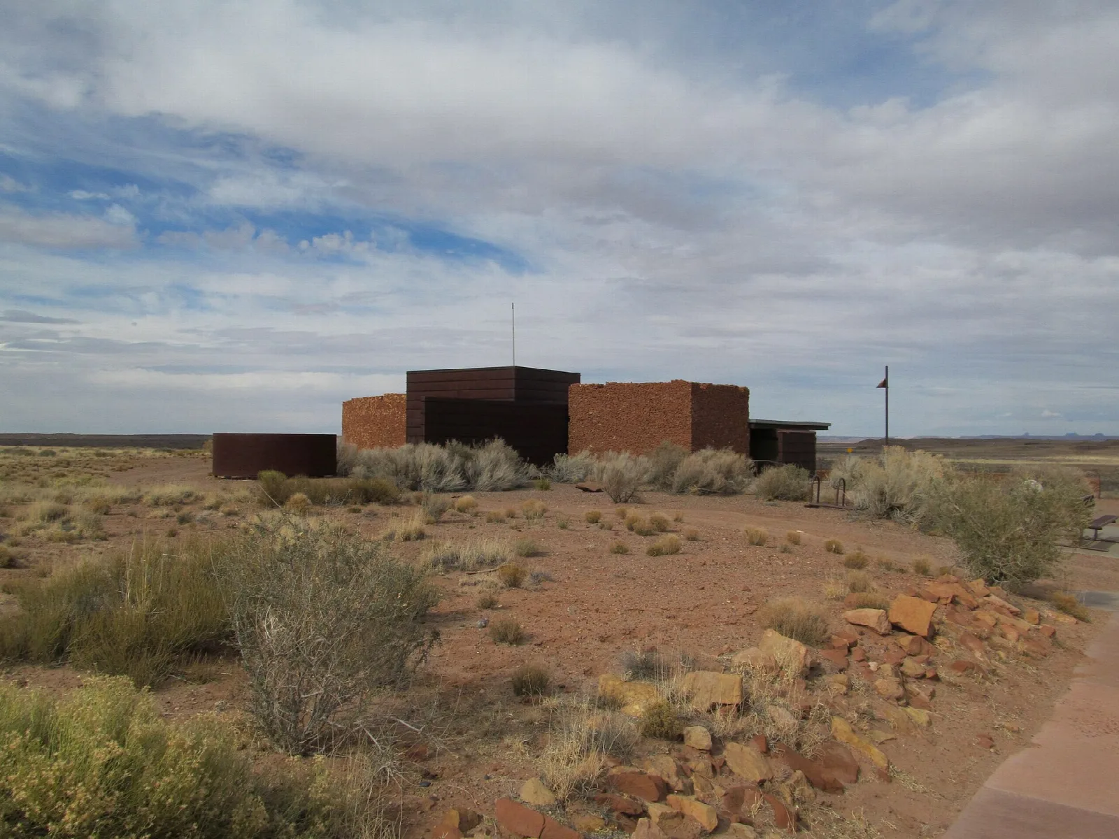 Low modern visitor center building on a flat desert plain under clouds