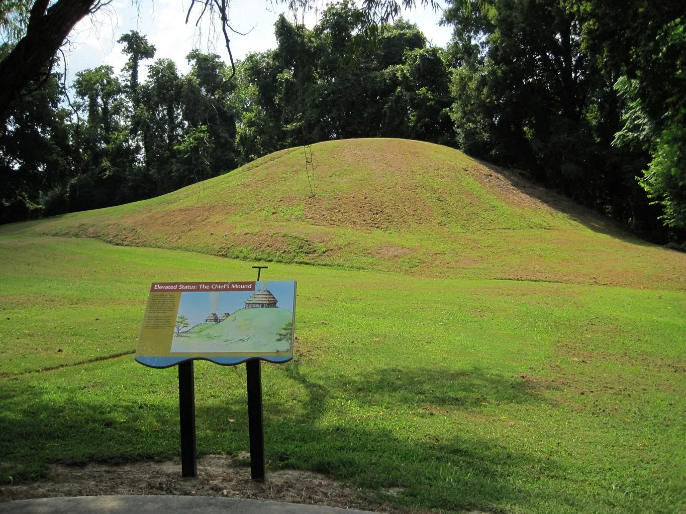 Grassy mound with an interpretive sign in front of it