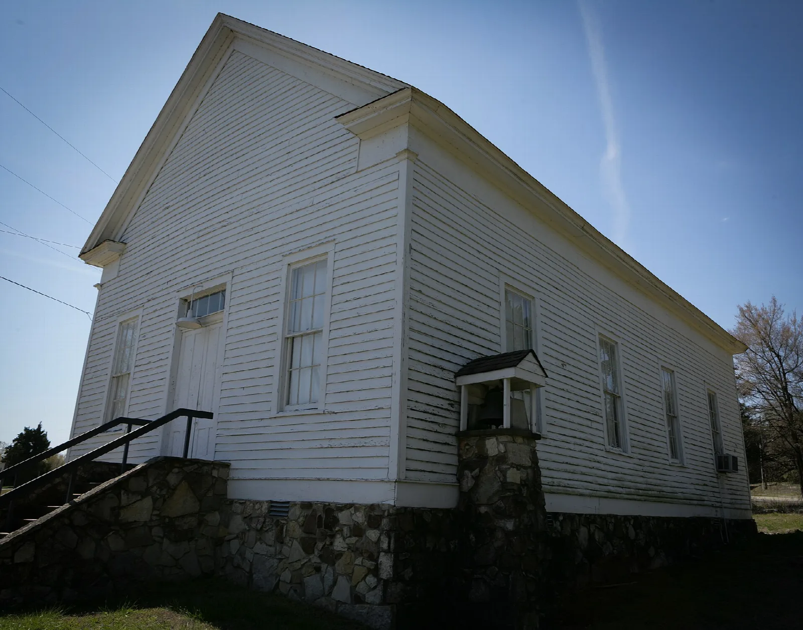 White wooden church with a stone foundation and a small porch