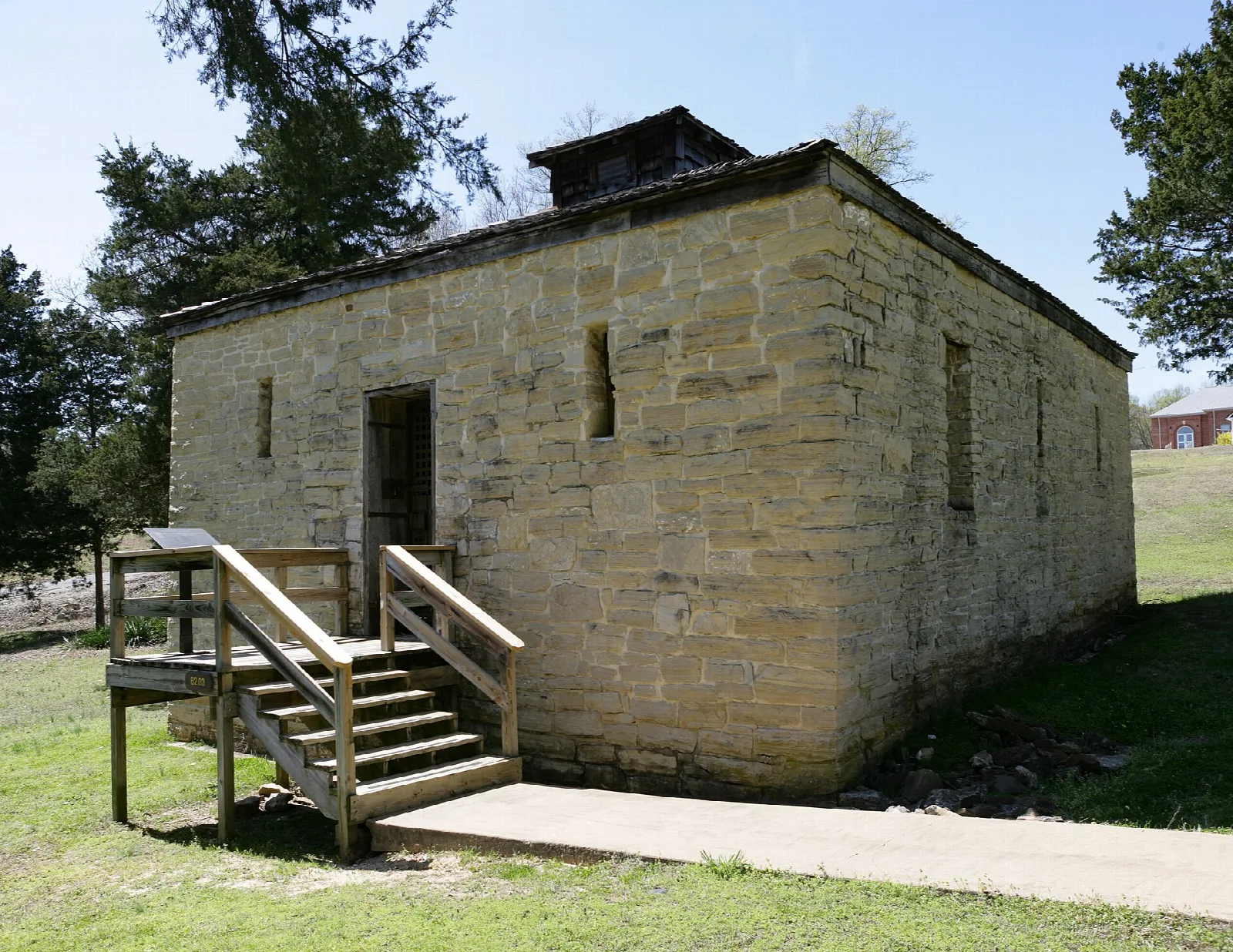 Small square stone jail building with wooden steps
