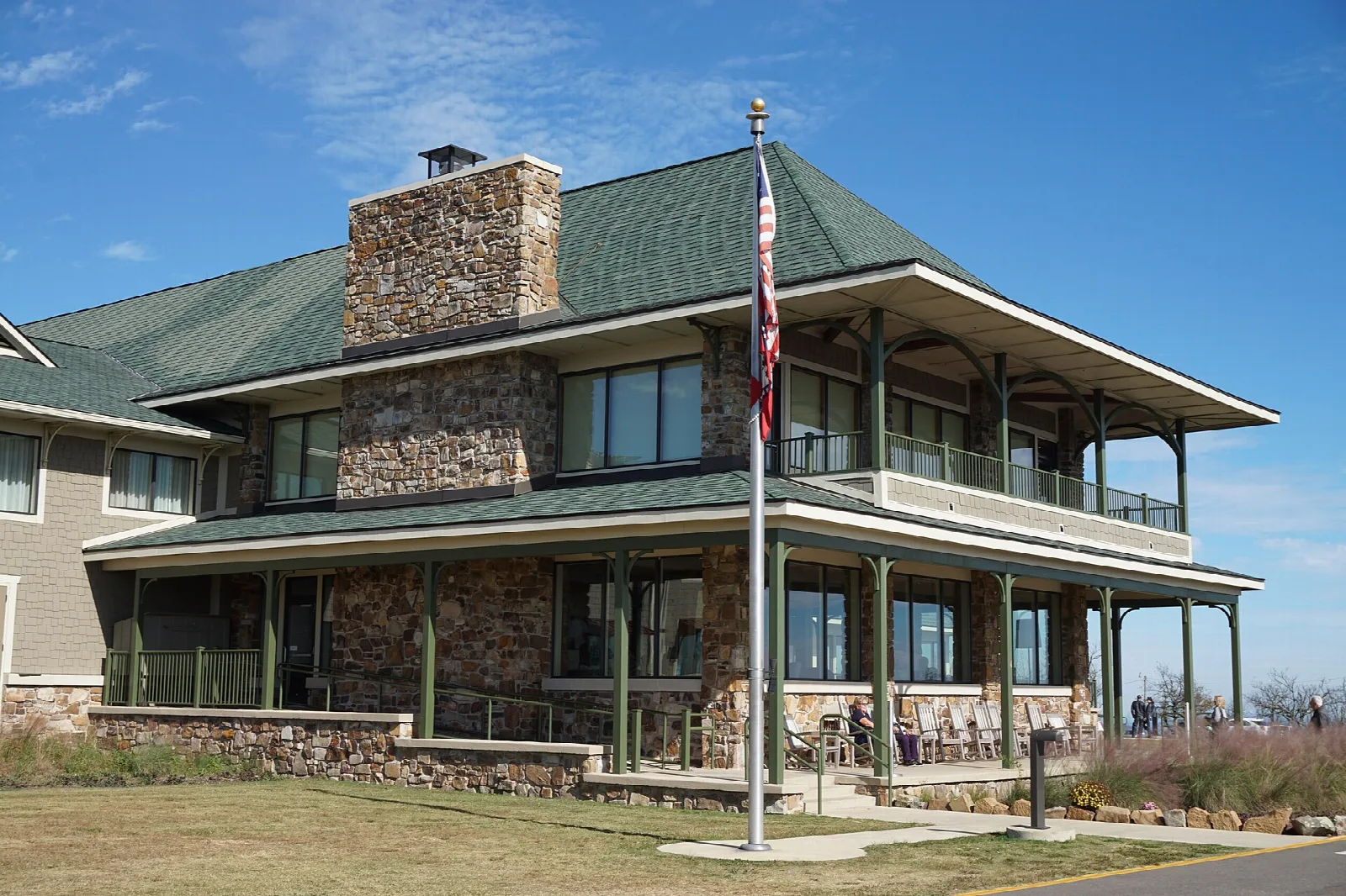 Two-story lodge with a stone chimney, green roof and a flagpole