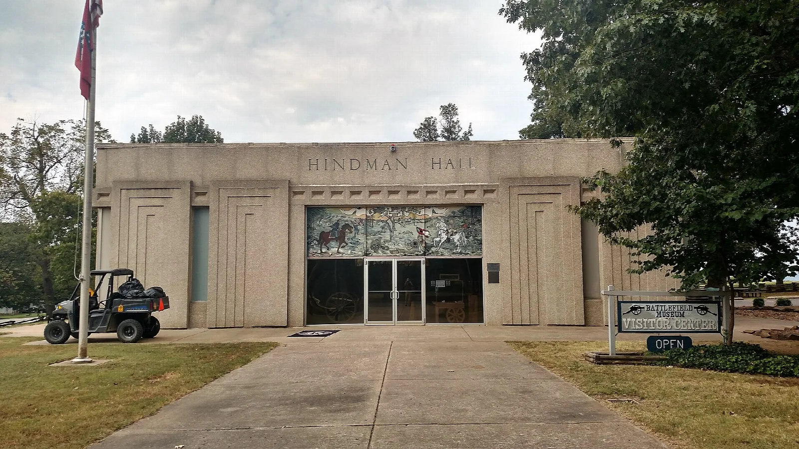 Tan flat-roofed museum building with a flagpole and a walkway
