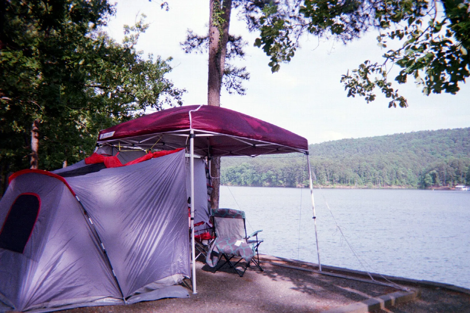 Tent and canopy on a lakeshore campsite with the lake and hills behind