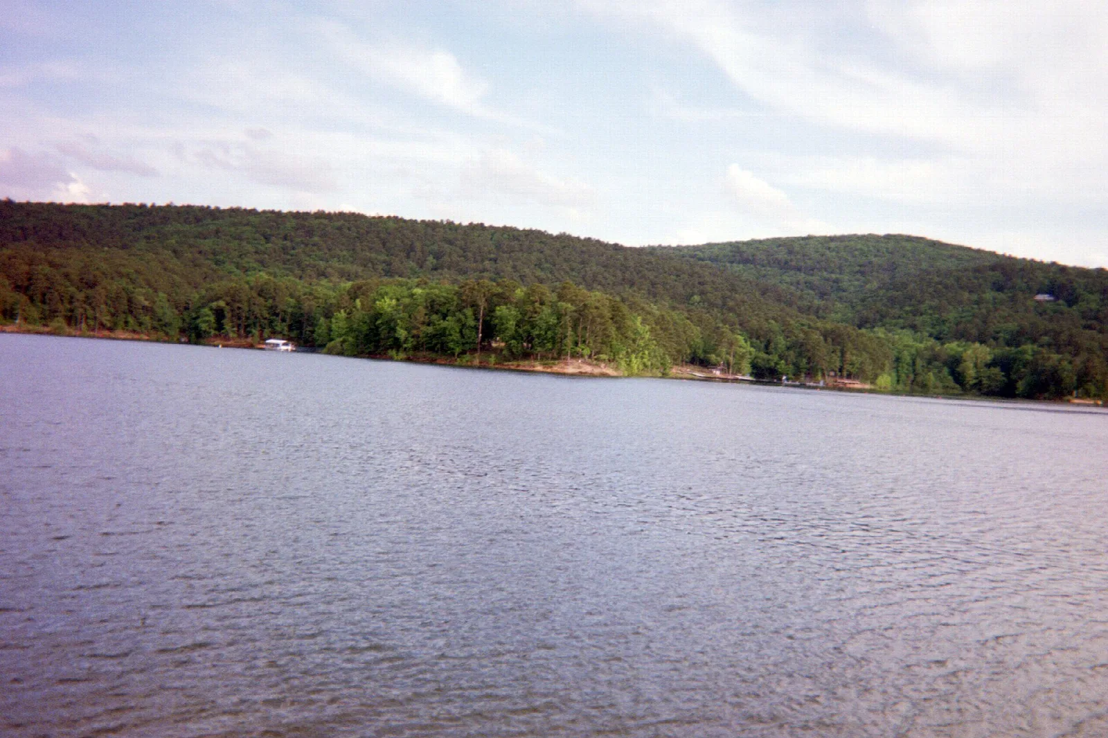 Wide lake with a tree-covered hillside on the far shore