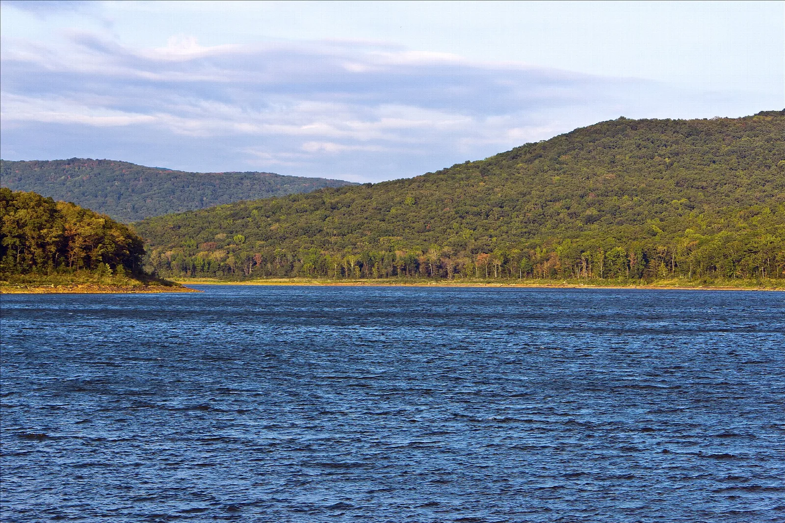 Wide blue lake with forested Boston Mountains rising behind it