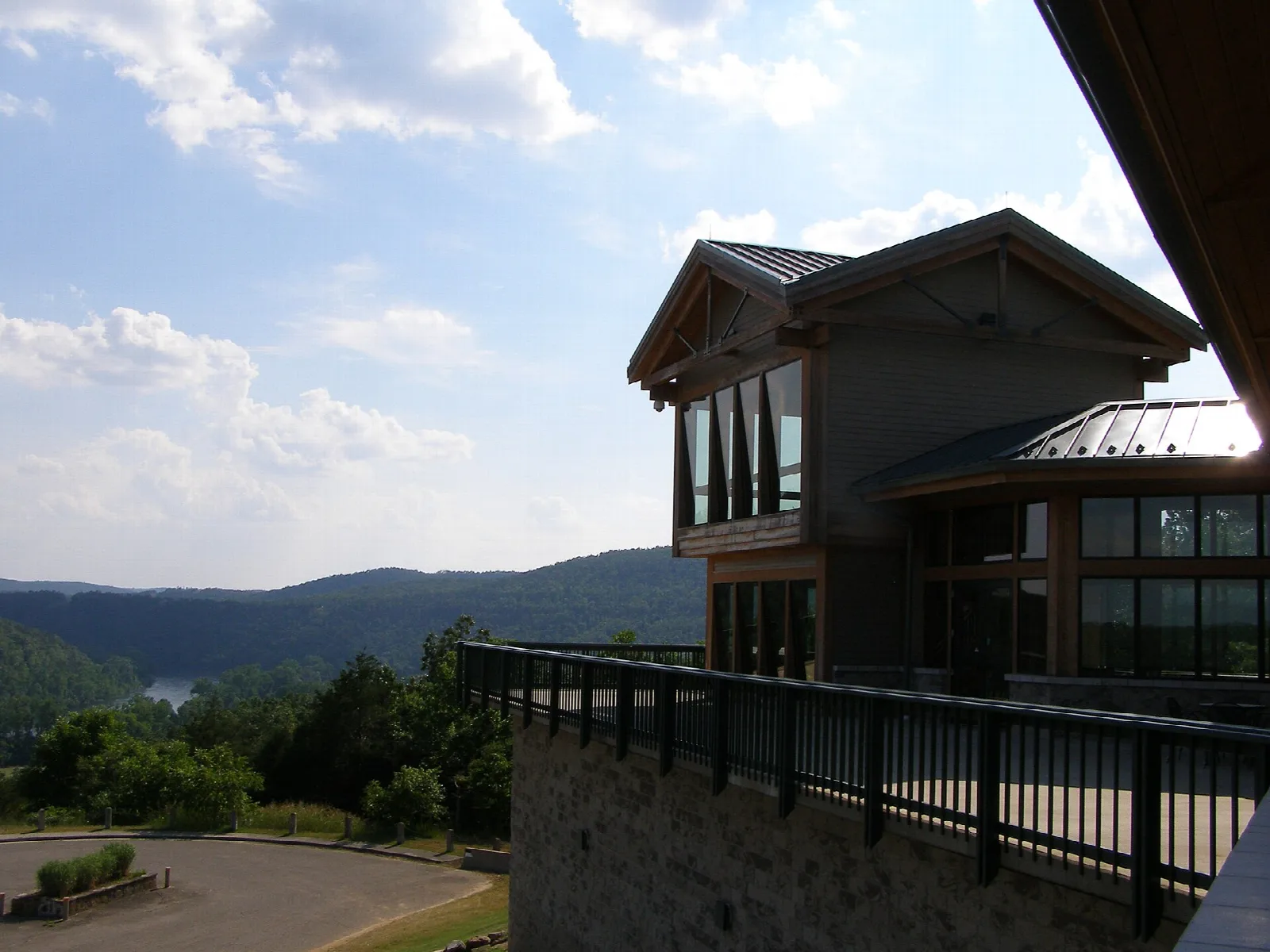 Glass-fronted visitor center on a hilltop with railing and distant hills