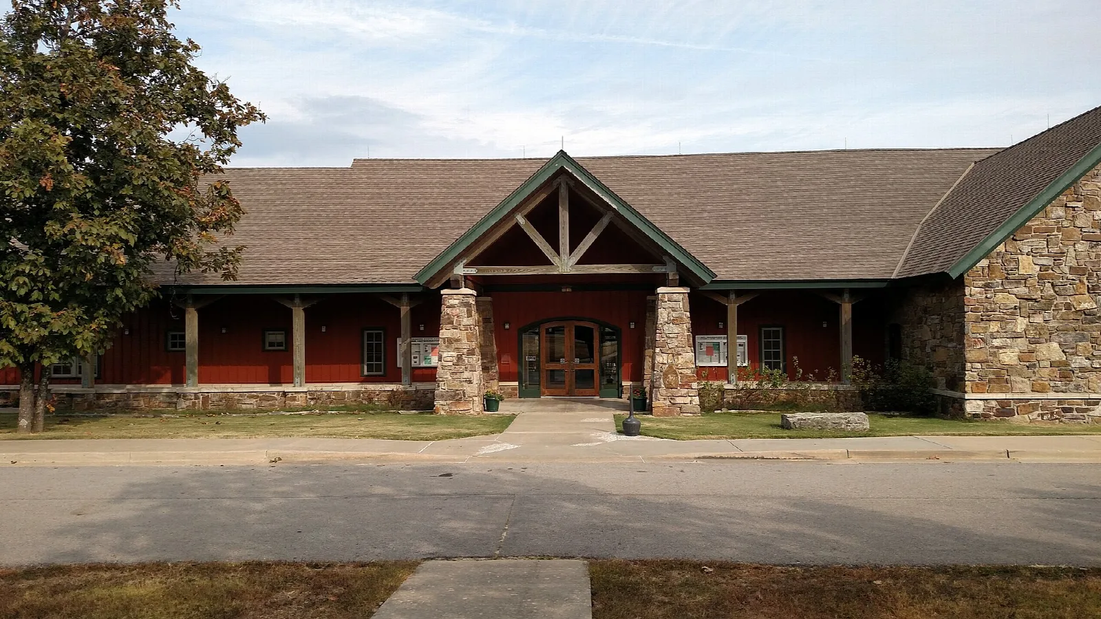 Low stone and timber visitor center building with a paved entrance