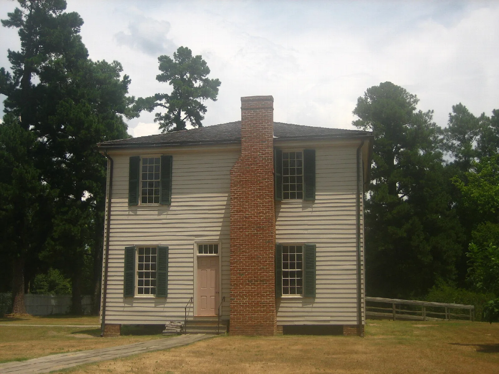 Two-story white frame courthouse with a tall brick chimney on a grassy lawn