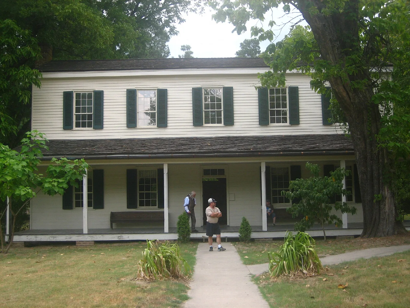 Long two-story white house with green shutters and a front porch