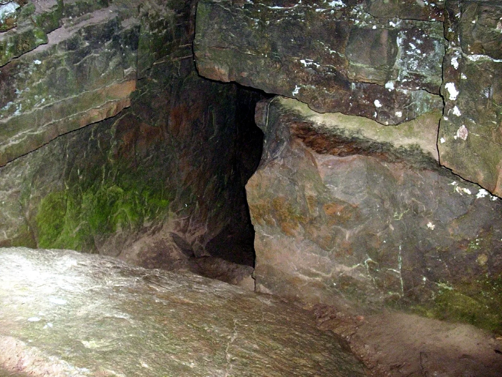 Dark cave opening in layered sandstone rock
