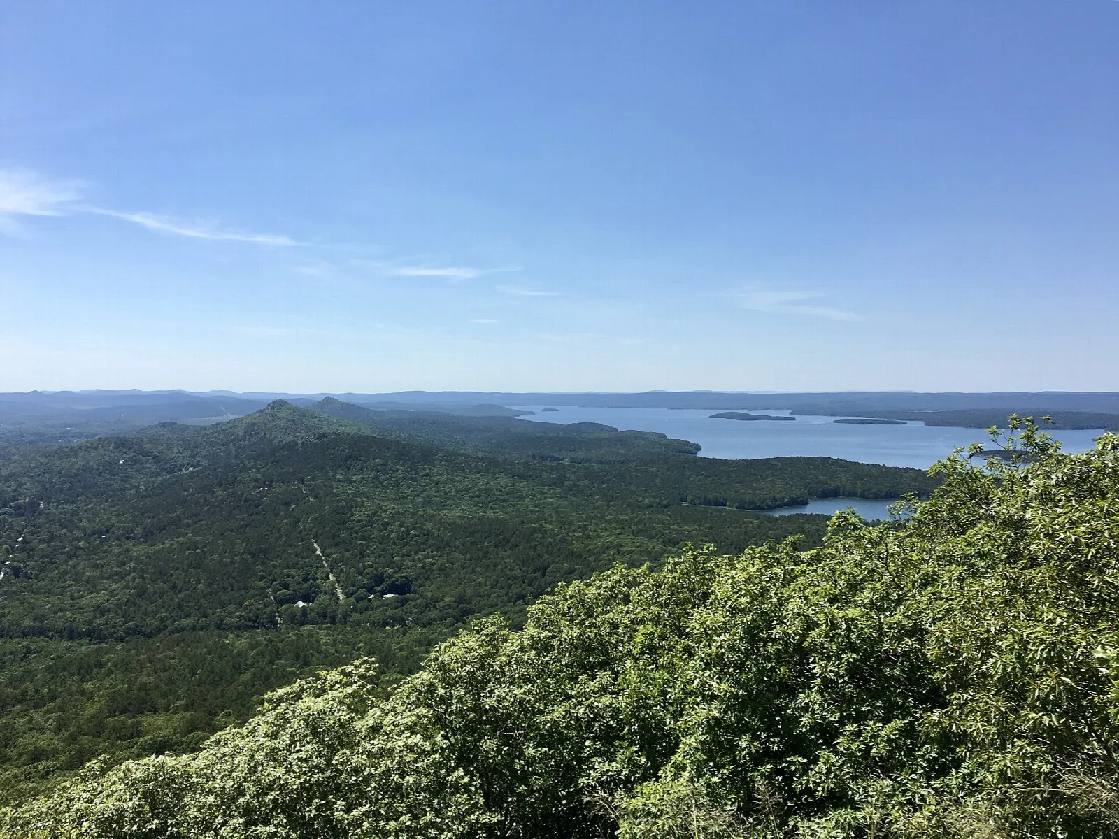 View from a summit over green forested hills and a distant river
