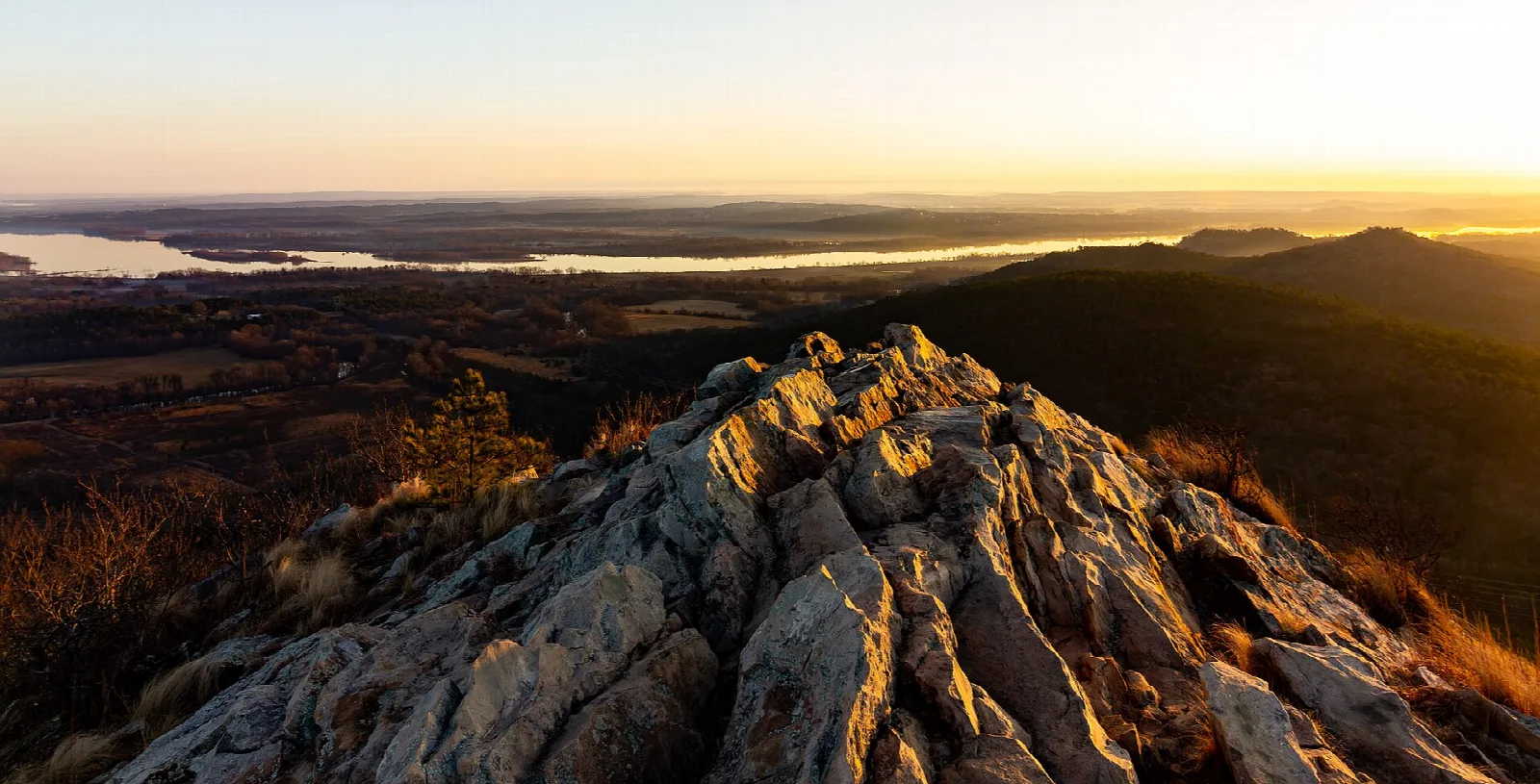 Sunrise light on a rocky ridge above a wide river valley